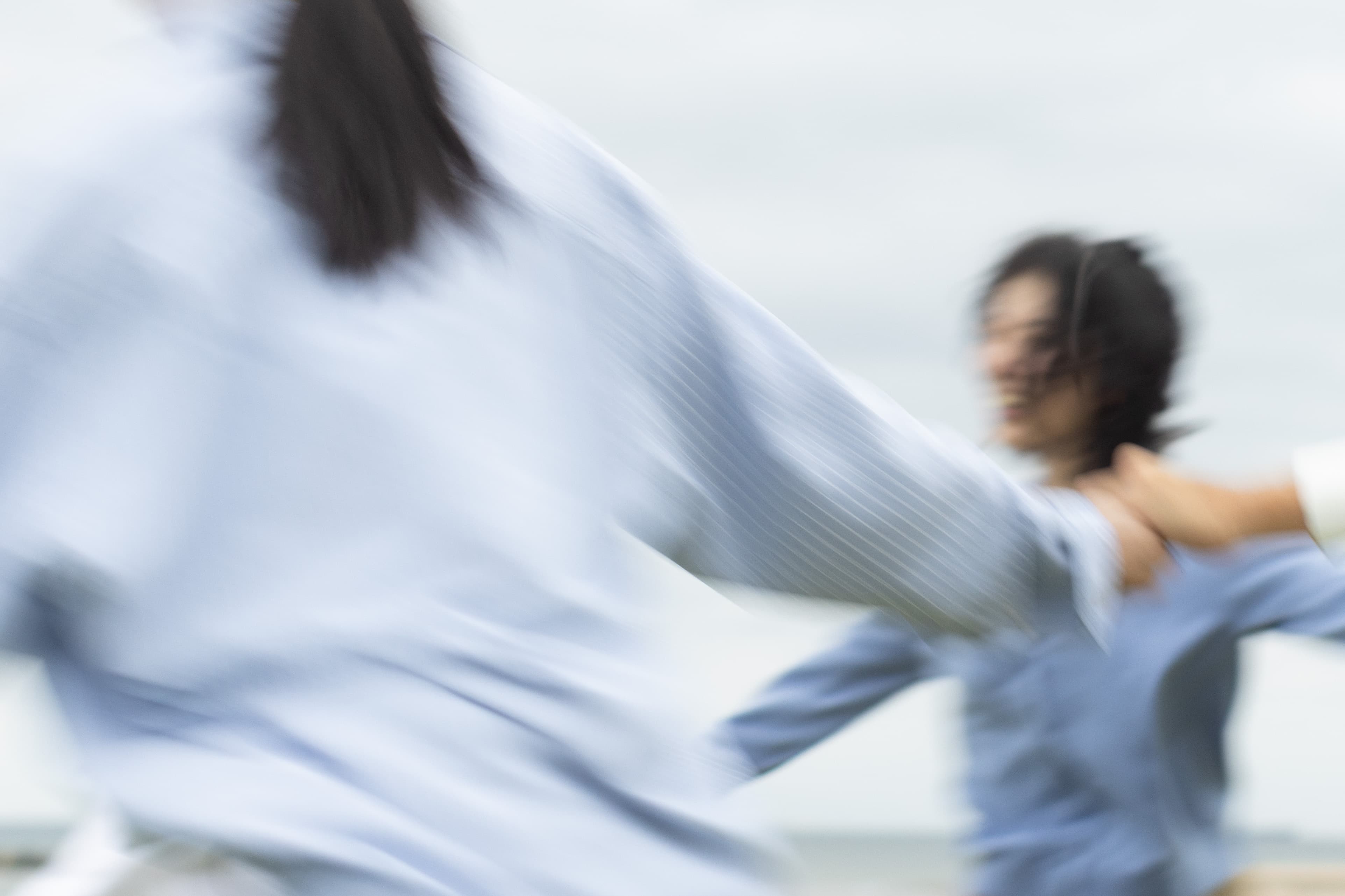 People in motion wearing light blue shirts in a photograph by Osamu Yokonami